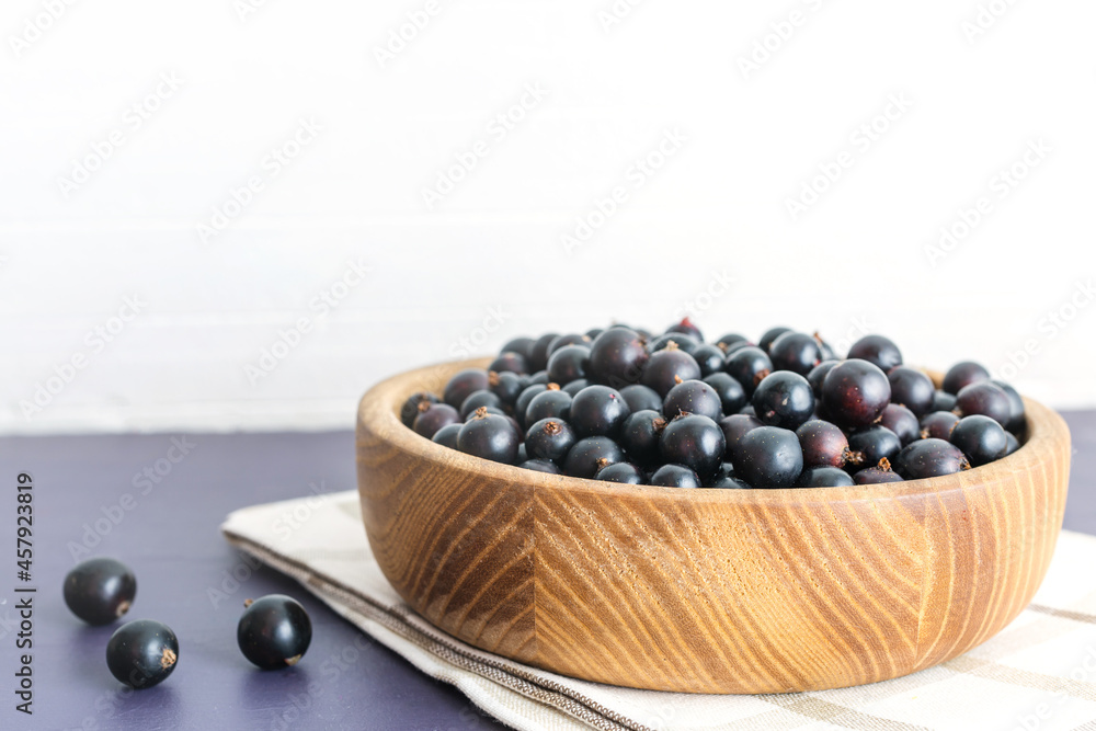 Fresh black currant in wooden bowl on dark table Fresh black currant in wooden bowl on dark table