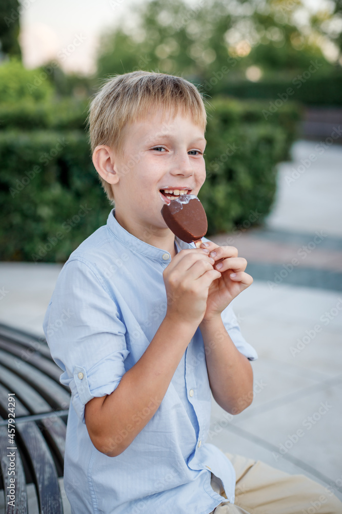 blonde boy in blue shirt eating popsicle ice cream blonde boy in blue shirt eating popsicle ice cream