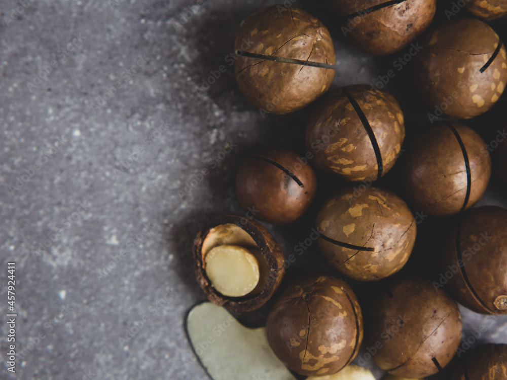Obraz premium pile of macadamia nuts close up on gray concrete background, copy space