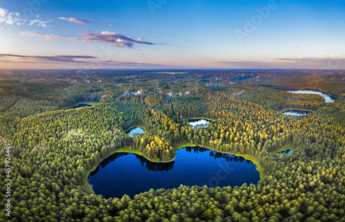 Obraz na płótnie Aerial view of sunrise over a pine forest with lake. Foggy and colorful morning in countryside. w salonie