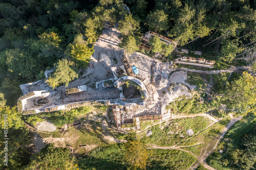 Aerial view of medieval Blatnica Gothic hilltop castle ruin above the village in a lush green forest area with towers and restoration work in Slovakia © tamas