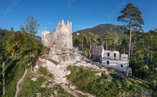 Aerial view of medieval Blatnica Gothic hilltop castle ruin above the village in a lush green forest area with towers and restoration work in Slovakia photo