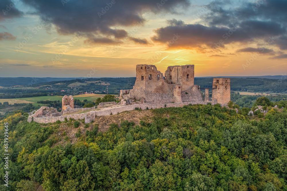 Aerial view of historic Csesznek castle ruin in the Bakony mountain in Hungary with newly restored lower castle dramatic colorful sunset sky