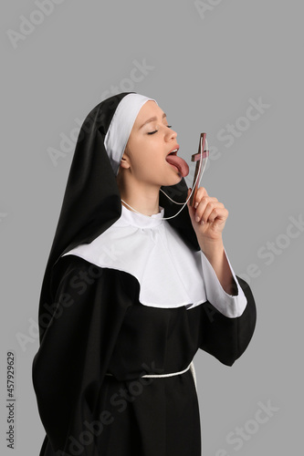 Sexy nun with cross on grey background photo