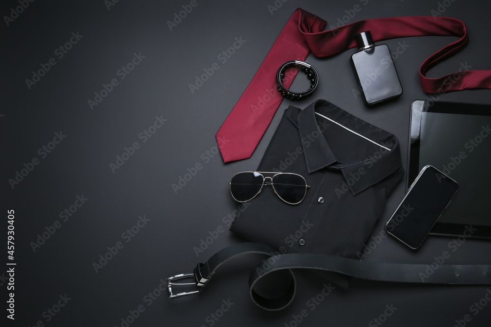 Stylish male clothes with accessories, mobile phone and tablet computer on dark background