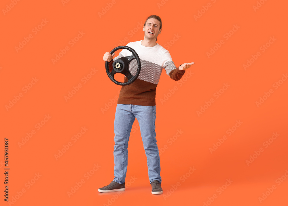Angry young man with steering wheel on color background Angry young man with steering wheel on color background