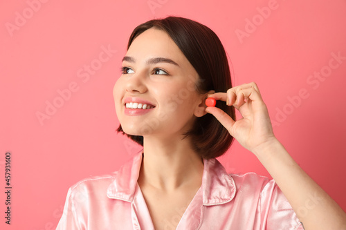 Young woman putting ear plu...