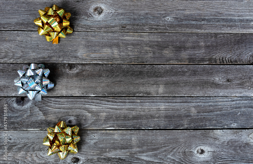 Left border of silver and gold bows on wooden background for a merry Christmas or happy New Year holiday celebration concept Left border of silver and gold bows on wooden background for a merry Christmas or happy New Year holiday celebration concept