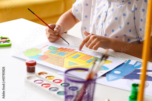 Cute little girl painting a...