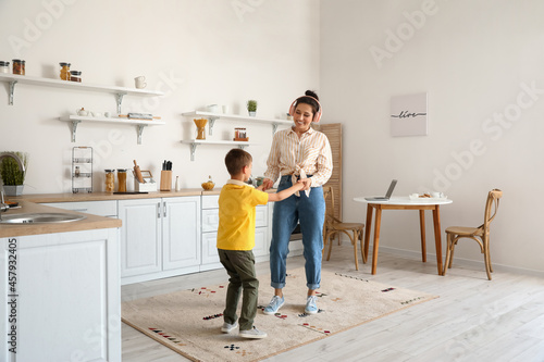 Young woman and her little son dancing and listening to music in kitchen © Pixel-Shot