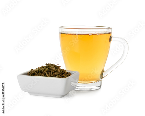Glass cup and bowl with dry hojicha green tea on white background