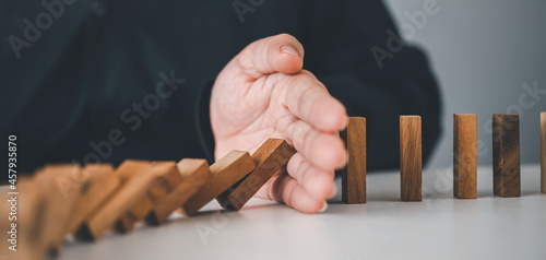 close-up hand The hand of a businessman who is stopping or preventing a falling block.Risk protection concept,Eliminating the risk.