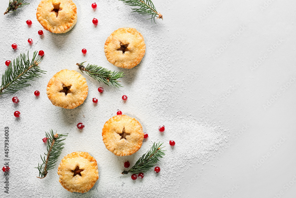 Composition with tasty Christmas mince pies, cranberry and fir branches on light background Composition with tasty Christmas mince pies, cranberry and fir branches on light background