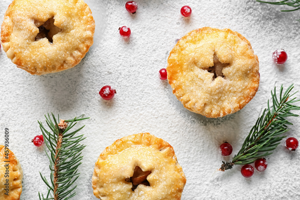 Tasty mince pies, cranberry and fir branches on light background