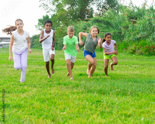 Barefoot kids running on green grass on field in summertime. © JackF