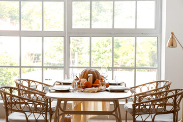 Dining table with pumpkins near window in room