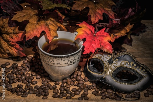 cup of coffee , mask and orange leaves