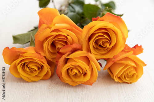 decorating a wooden table with a bouquet of yellow roses with a freshly flowered orange edge  detail of the petals and texture  nature in studio  romantic gift