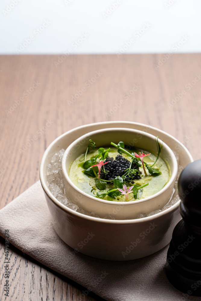 Ice cold gourmet soup with spinach and flowers as a decoration, top view, menu photo Ice cold gourmet soup with spinach and flowers as a decoration, top view, menu photo