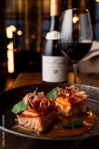 Salmon and wine, a classic fish restaurant set on blurred lights background, side view, close up