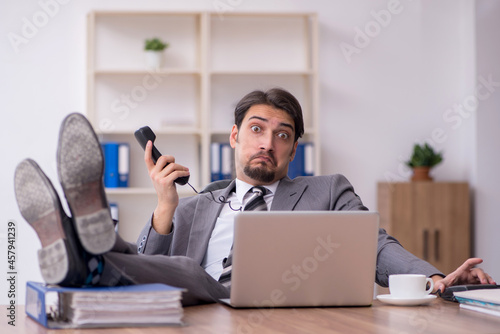 Young attractive male employee sitting at workplace