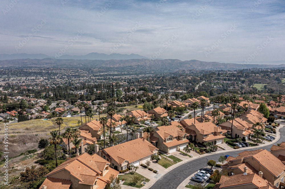 Aerial view of a suburban southern California community in the hills.  Sunny day with silky clouds
