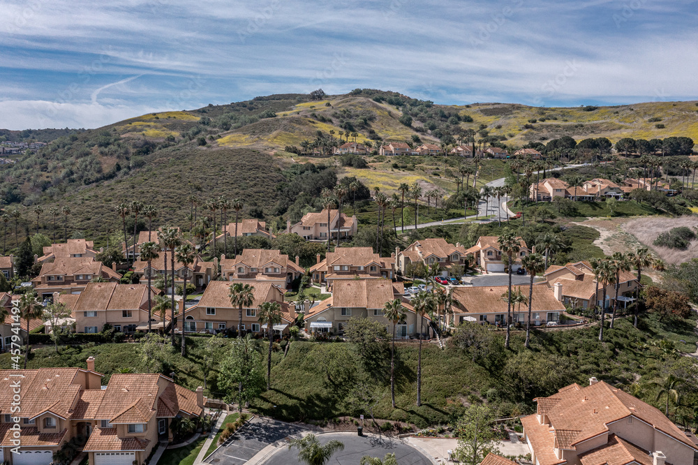 Aerial view of a modern southern California neighborhood on a hill with silky clouds.
