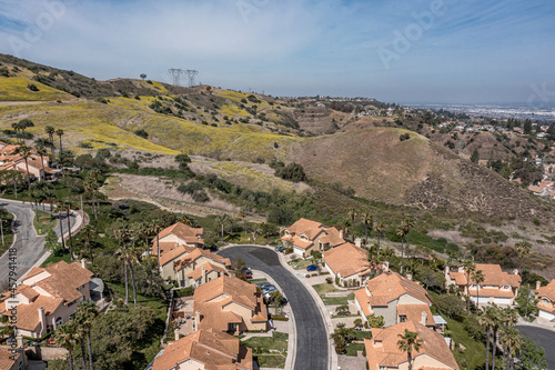 Aerial view of a suburban southern California community in the hills.  Sunny day with silky clouds, power lines visible