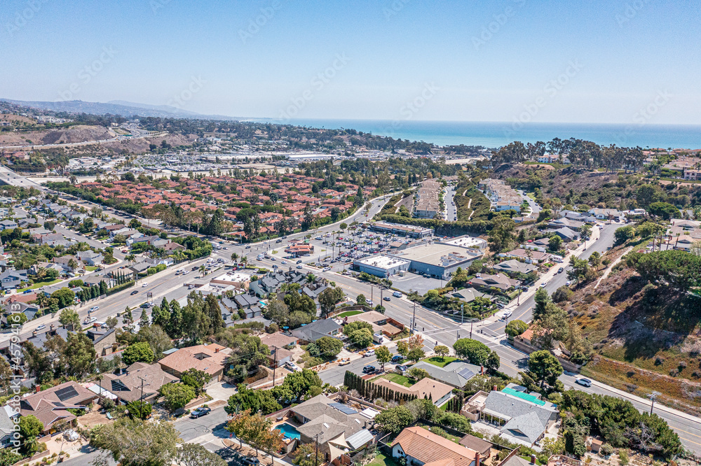 Aerial view of a southern California coastal community on a hill with a highway running through and ocean in the background