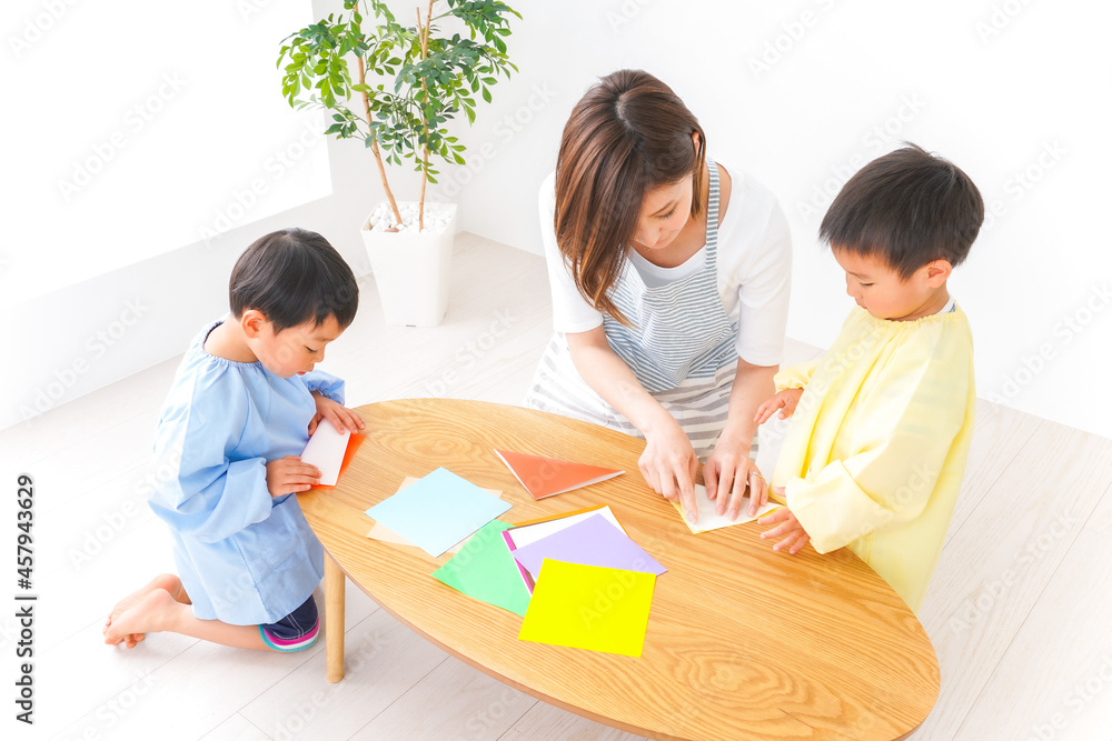 幼稚園で折り紙をする子どもと先生