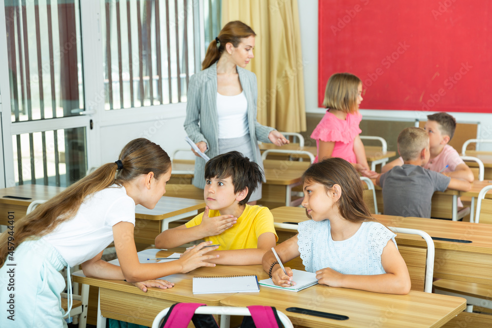 Obraz premium Focused tweens working in small groups during lesson at school, discussing assignment given by teacher. Teamwork concept
