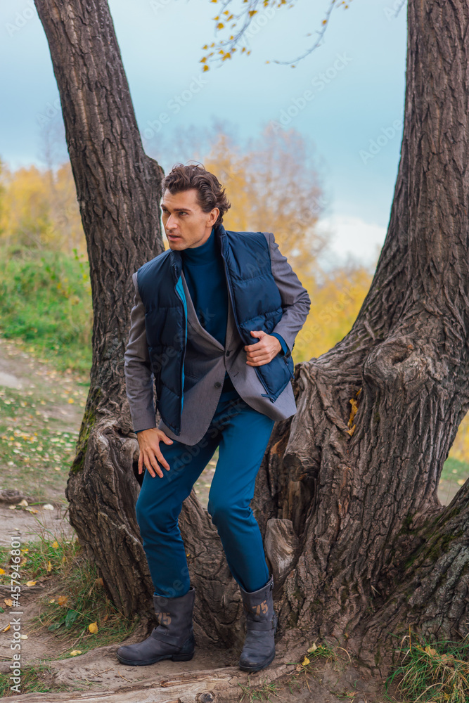 Tall handsome man standing near the tree in autumn forest Tall handsome man standing near the tree in autumn forest