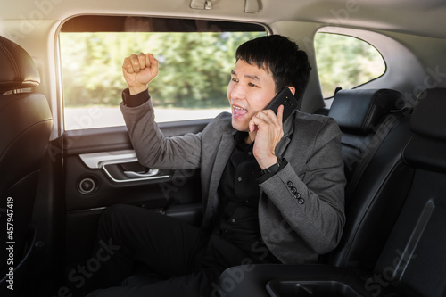 successful business man talking on a mobile phone while sitting in the back seat of car