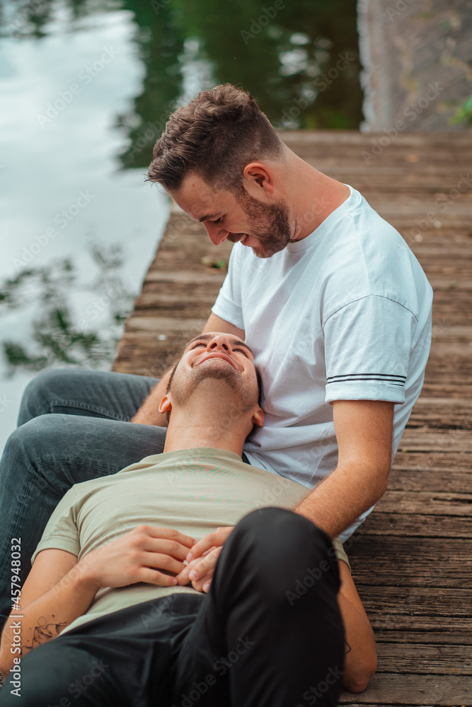 gay couple sitting on the edge of a lake gay couple sitting on the edge of a lake
