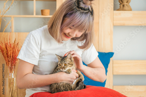 young woman playing with cat in living room at home