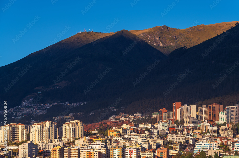 Quito city skyline at sunrise with modern high rise apartment building with Pichincha volcano, Ecuador.