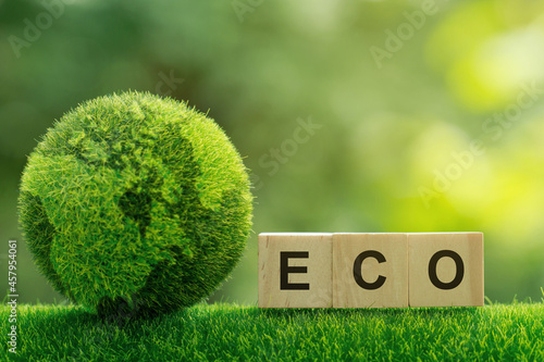 Words ECO on a woodblock on green sunny background. Saving environment, save clean planet, ecology concept.eco-friendly agricultural products. Reducing human intervention in ecosystems. 