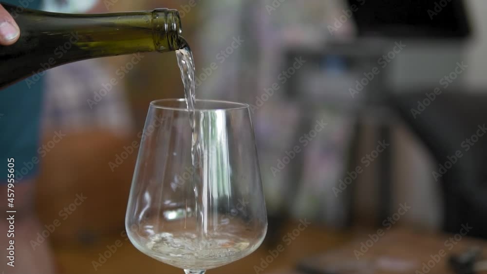 Woman or man pours white wine or champagne into a glass. Closeup shot Woman or man pours white wine or champagne into a glass. Closeup shot