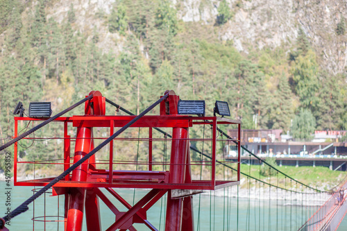 A suspension bridge over a wide river in the mountains. Safe crossing of the bridge from one bank to the other.