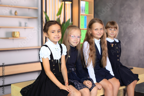 Young female students in school uniforms before the lesson in the classroom. Remote education. The company of schoolgirls in the classroom. Primary school photo