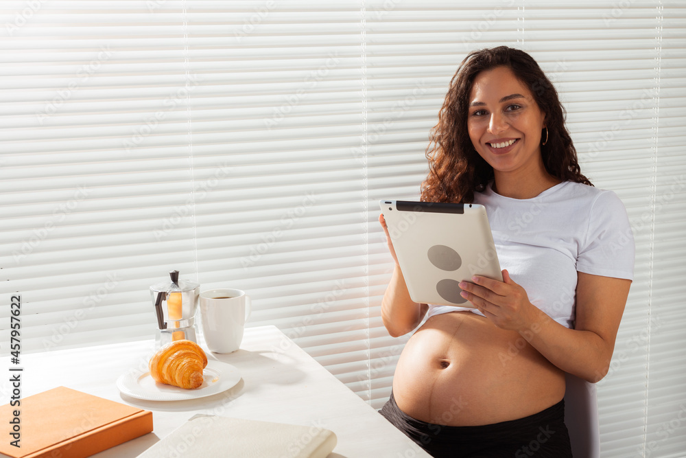 Pregnant woman using digital tablet. Breakfast time. Technology and pregnancy concept. Pregnant woman using digital tablet. Breakfast time. Technology and pregnancy concept.
