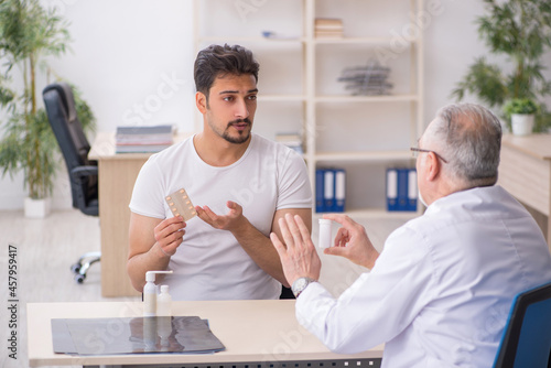 Old male doctor suggesting pills to young male patient