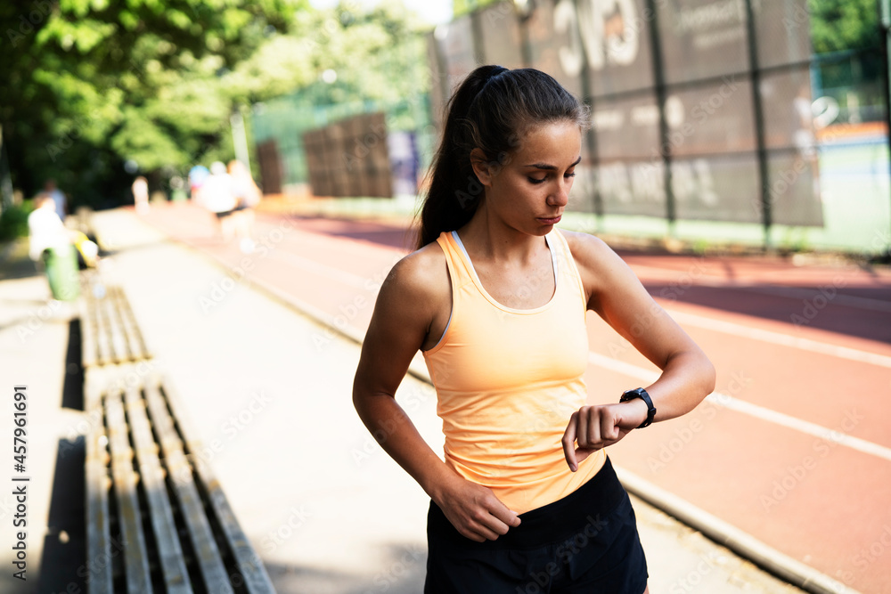 Young beautiful woman training outdoors. Female runner using smart watch.. Young beautiful woman training outdoors. Female runner using smart watch..