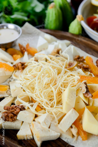 Cheese tasting with herbs and fruits on the rustic vintage table. Gerogian cuisine concept, traditional cheese platter. photo