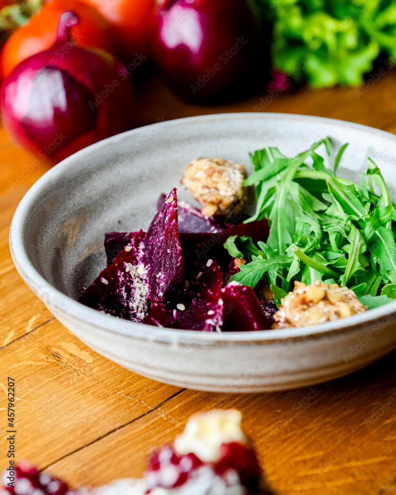 Salad with grated beets and herbs in a bowl on the rustic wooden background with a lot of fresh greenery. Salad with grated beets and herbs in a bowl on the rustic wooden background with a lot of fresh greenery.