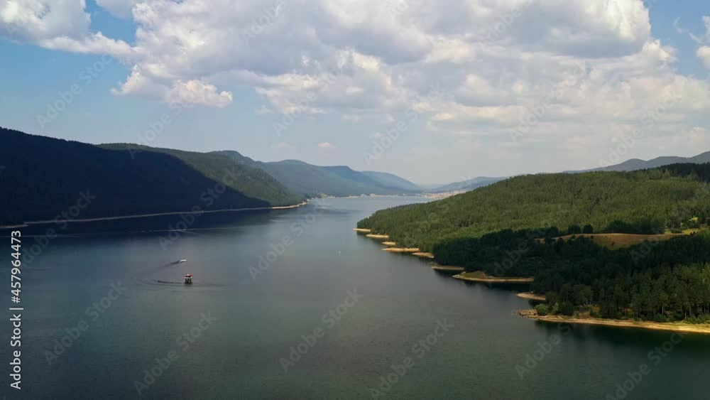 Slow aerial pan shot over Dospat resrervoir,Rhodopes Bulgaria with motor boat heading along the dam Slow aerial pan shot over Dospat resrervoir,Rhodopes Bulgaria with motor boat heading along the dam
