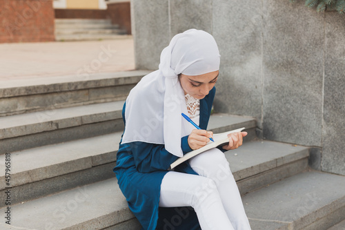 Arab female student sitting on stairs in downtown.