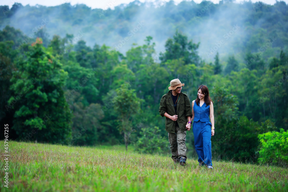 portrait of romantic asian couple embracing while walking in the green field copy space