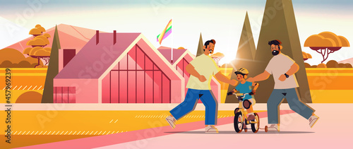 male parents teaching little son to ride bike gay family transgender love LGBT community concept