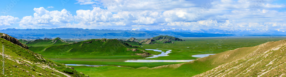 Bayinbuluke grassland natural scenery in Xinjiang,China.The winding river is on the green grassland.Panoramic view. Bayinbuluke grassland natural scenery in Xinjiang,China.The winding river is on the green grassland.Panoramic view.
